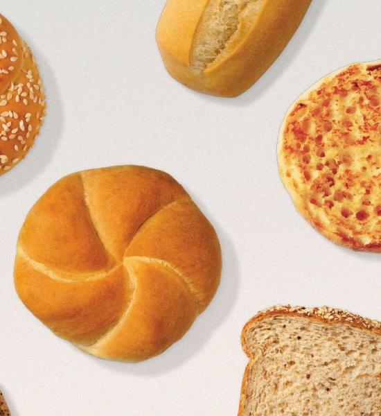 Freshly baked rye bread, english muffin, wheat bread, sesame seeds bun on a table.